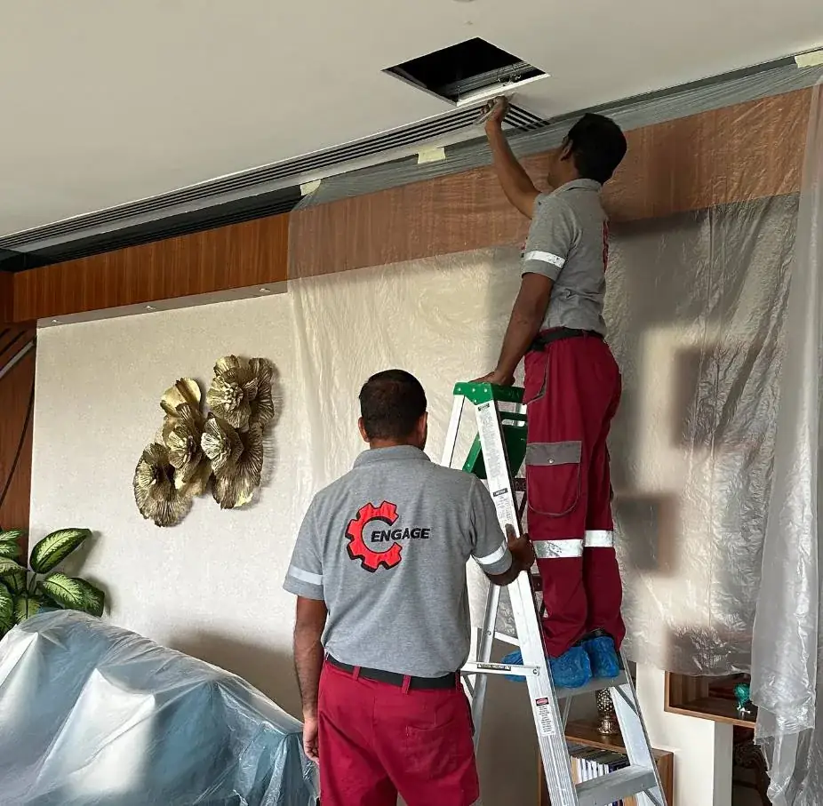 Engage technicians servicing a ceiling AC unit